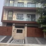 Four-floor builder floor front elevation with jali screen, glass balconies and wooden cladding by GharVistaar builder floor construction Delhi